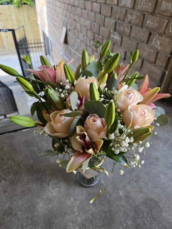 Purple hydrangea and pink chrysanthemum bouquet held up in front of a luxury Houston home at sunset by Lola in Bloom florist